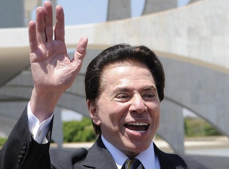 Um homem branco sorri e acena