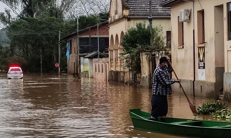 Uma pessoa anda num barco numa rua inundada pelas chuvas