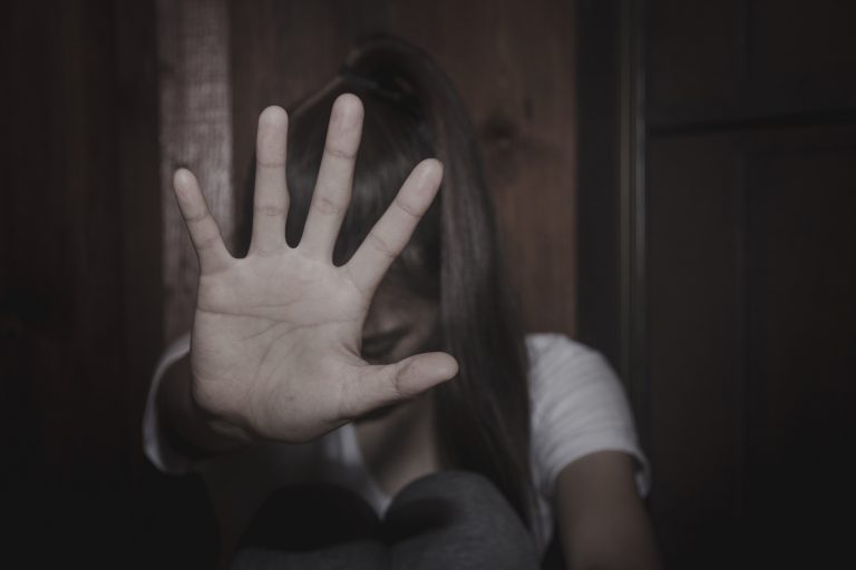 Mulher encolhida fazendo sinal de pare com a mão