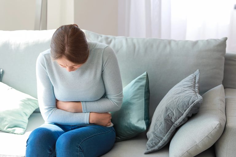 Mulher com cólica sentada no sofá